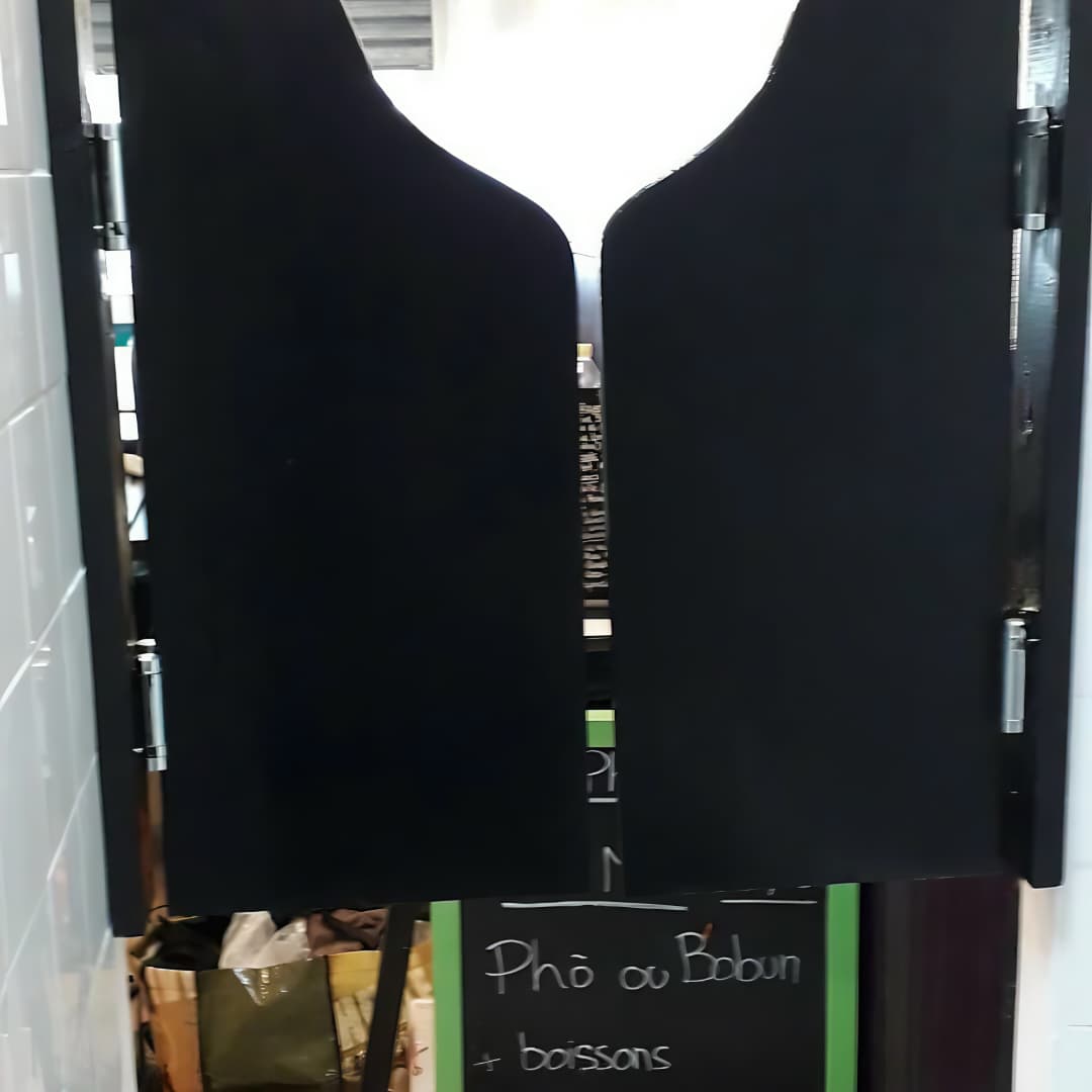 Un panneau de menu / ardoise de restaurant avec des volets ou battants noirs qui s'ouvrent, laissant deviner des inscriptions de plats (on distingue "Phô ou Bobun").