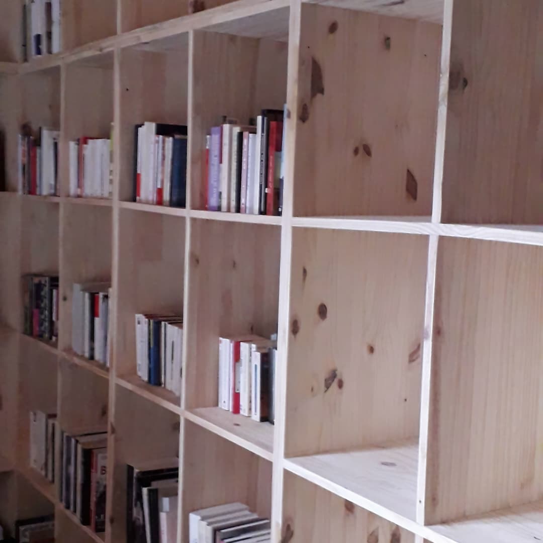 Un zoom ou une vue rapprochée d'une grande *bibliothèque à cases en bois (style étagère à casiers / cube de rangement) remplie de livres.
